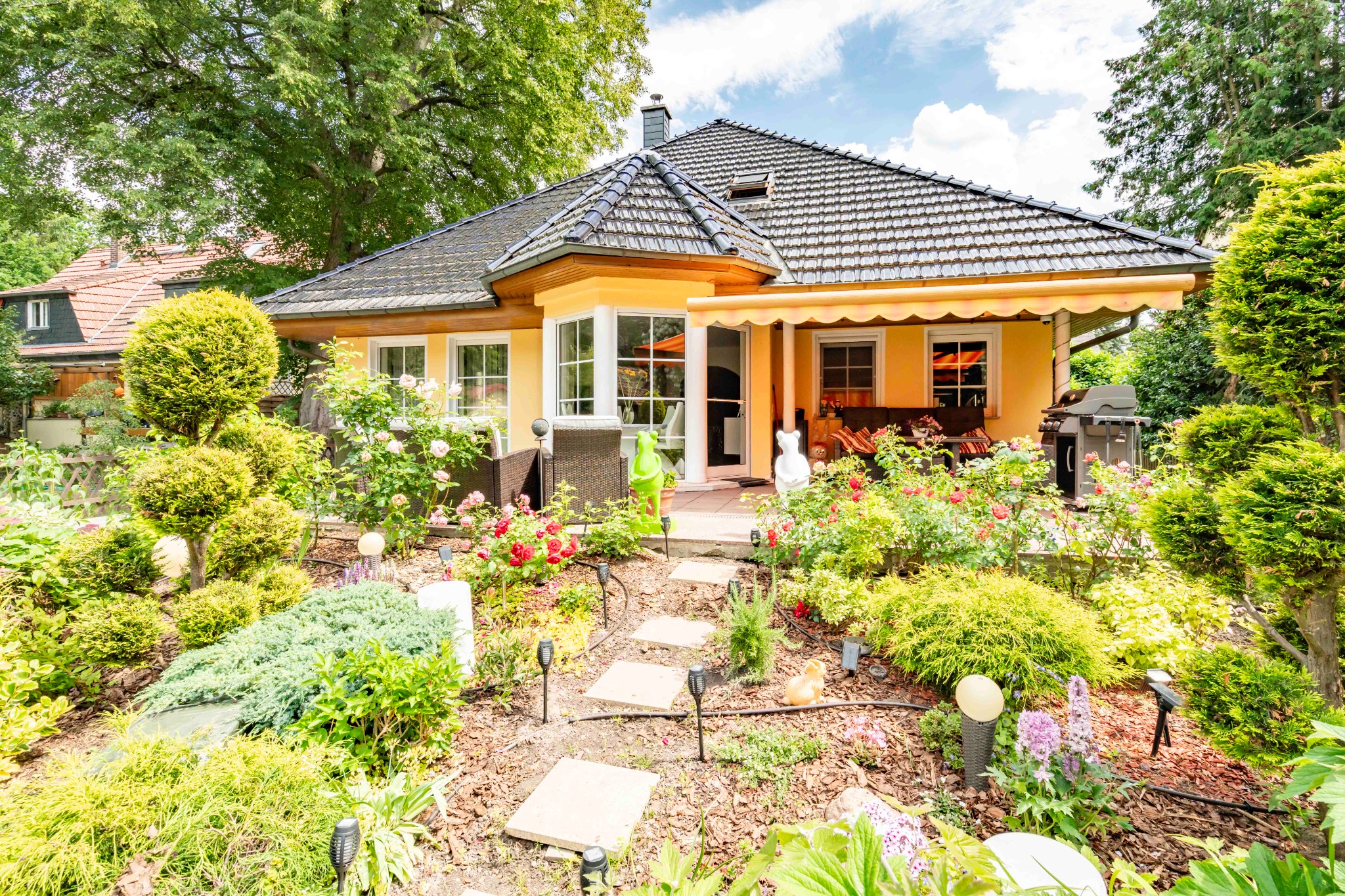Hausansicht mit blühendem Terrassengarten