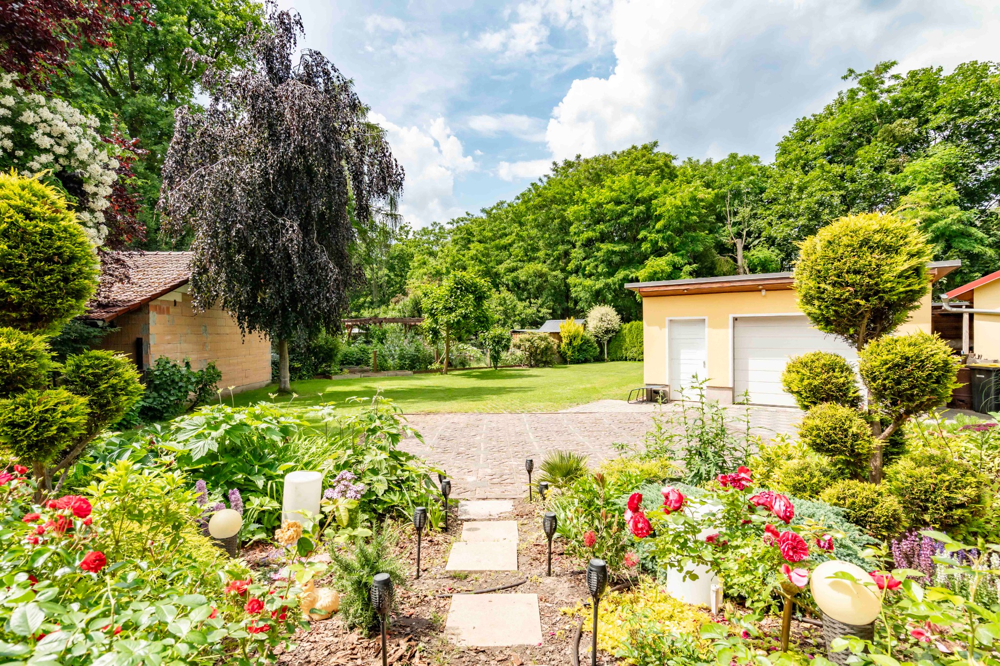 Blick über den Rosengarten zur Garage